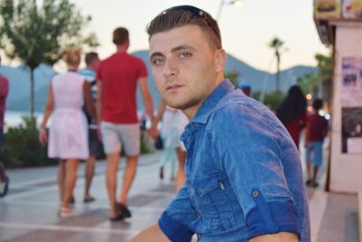 Portrait of man sitting on footpath during sunset