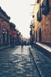 People walking on street amidst buildings in city