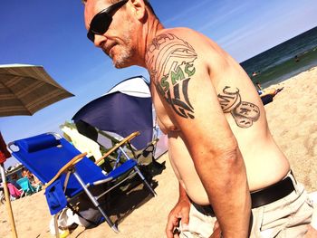 Shirtless mature man wearing sunglasses at hampton beach