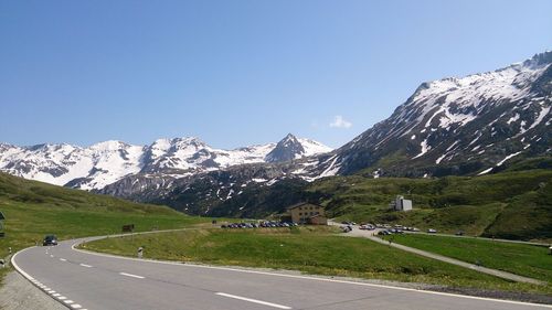 Road leading towards mountain against cloudy sky