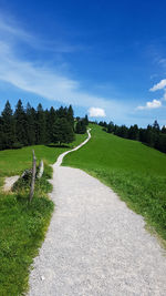 Empty road amidst field against sky