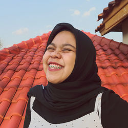 Portrait of smiling young woman against sky