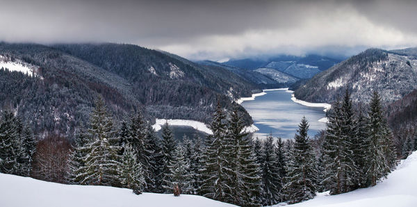 Panoramic view of frozen river amidst mountains during winter