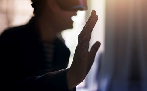 Midsection of woman wearing virtual headset at home