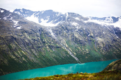 Scenic view of mountains by river against sky