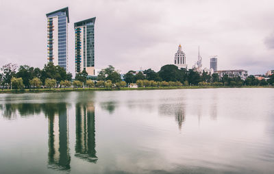 Scenic view of lake by buildings against sky in city