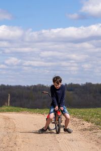 Full length of boy riding bike from the other side  on rural road
