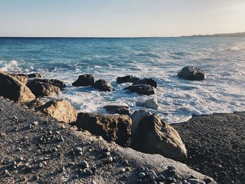 Scenic view of rocks in sea against clear sky