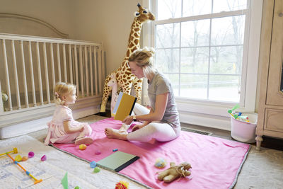 Mom and daughter look at each other while reading a book