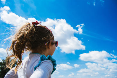 Low angle view of girl against blue sky on sunny day