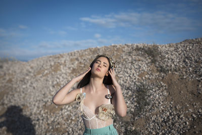 Young woman standing on beach against sky
