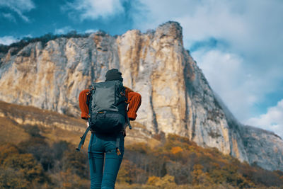 Rear view of woman standing on rock against mountain