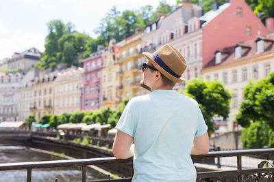 Young man standing by railing in city