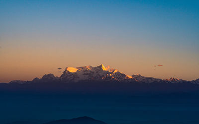 Scenic view of snowcapped mountains against clear sky during sunset