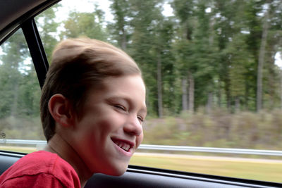 Happy boy looking through window of speeding car