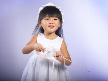 Portrait of cute girl in angel costume against purple background