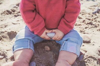 Low section of child sitting on sand