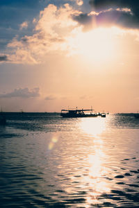 Silhouette boat in sea against sky during sunset