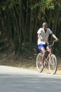 Portrait of a smiling young man with bicycle in forest