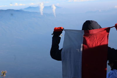 Rear view of men standing on mountain against sky