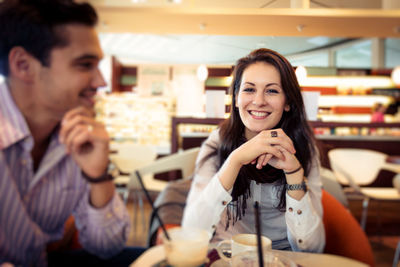 Portrait of smiling young woman eating food at restaurant