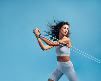 Woman exercising against blue background