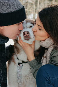 Couple kissing dog during winter