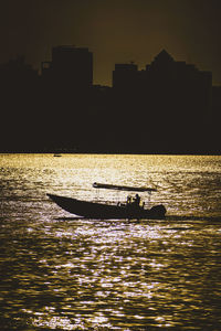 Silhouette people on sea against sky during sunset