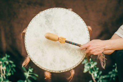 Cropped hands of person playing drum outdoors