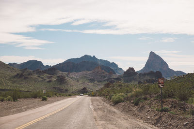 Road by mountains against sky