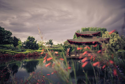 Panoramic view of temple by lake and building against sky