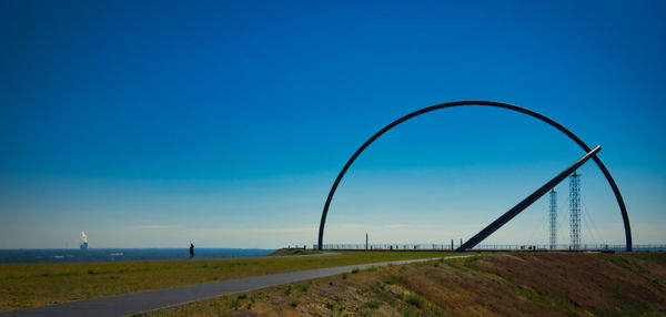 Road by land against clear blue sky