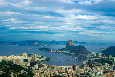 High angle view of city by sea against sky