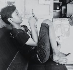 Side view of young woman sitting on floor at home