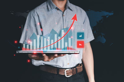 Digital composite image of man holding camera over black background