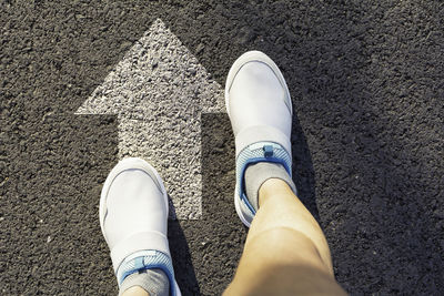 Low section of woman on arrow symbol over road