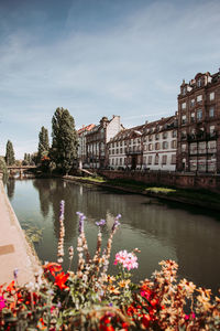 Scenic view of river by buildings against sky