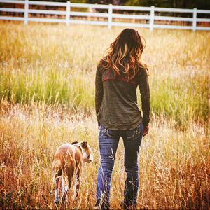 Rear view of woman with dog on field