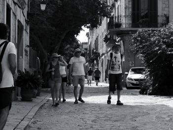 Rear view of people walking on street in city