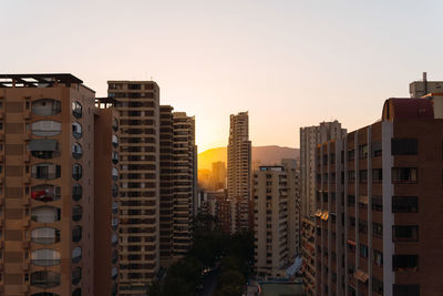 Aerial view of modern apartment buildings located against sundown sky on city street