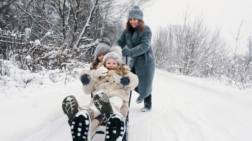 Family sledding in winter winter activity. happy laughing family woman with 2 daughters are enjoying