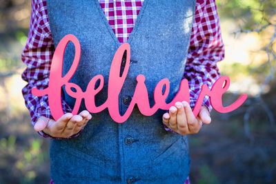 Midsection of man holding believe text outdoors