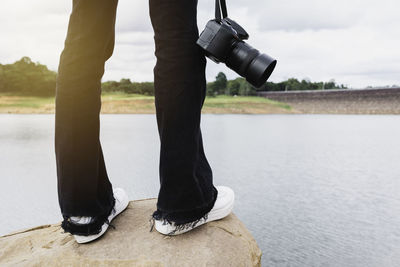 Low section of man standing on riverbank