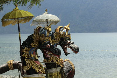 Statue by lake against sky