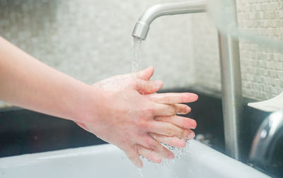 Cropped image of hand touching water in bathroom