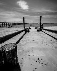 Wooden posts on beach against sky