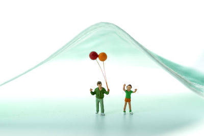 Digital composite image of people with balloon standing against white background
