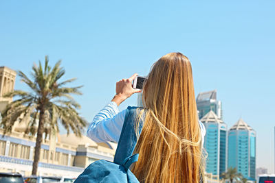 Rear view of woman photographing against sky