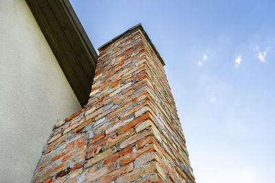 A red ceramic brick chimney standing at the rear of the building, by the facade.