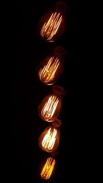 Low angle view of illuminated light bulb against black background